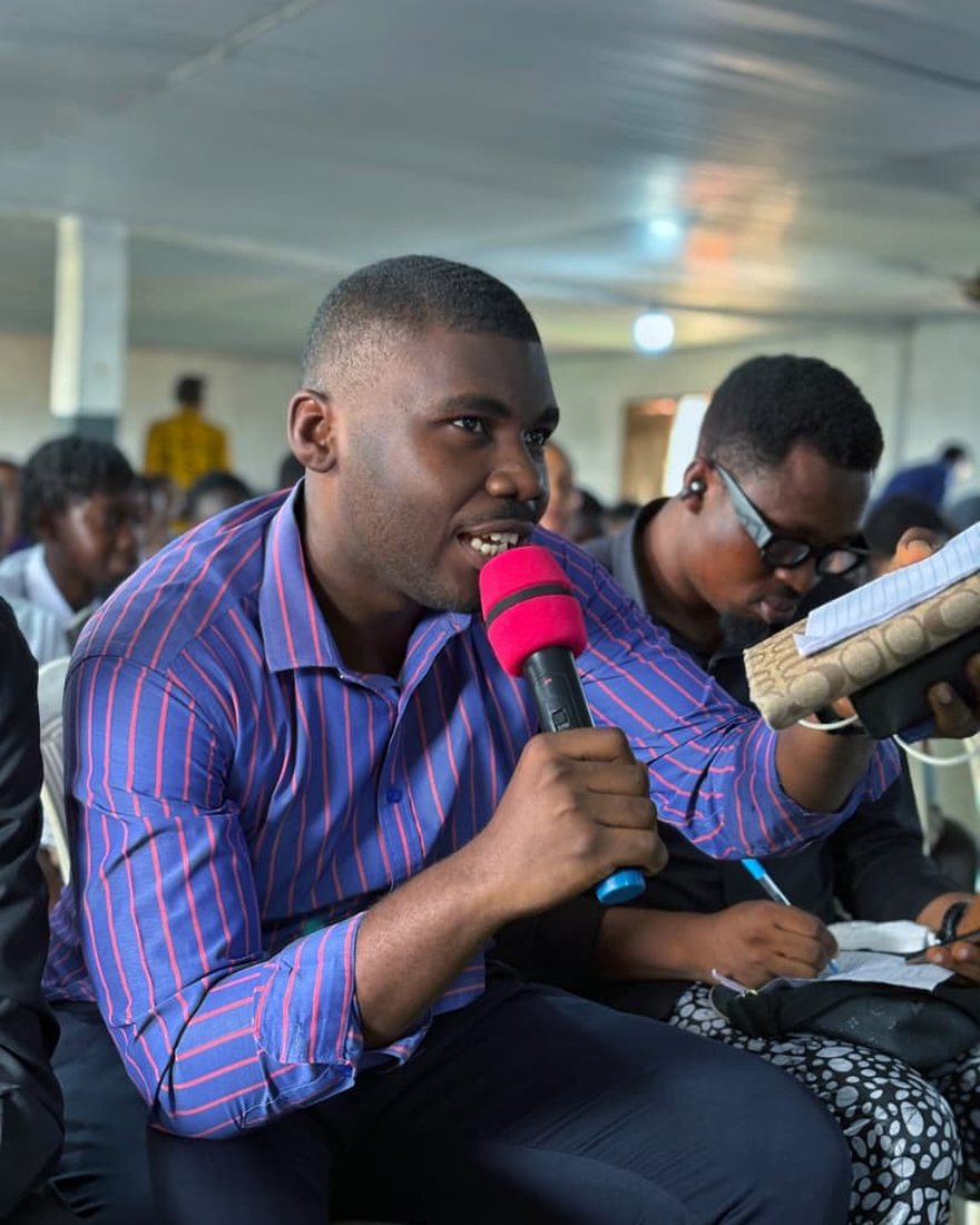 Fortune Johnson speaking into a microphone while holding a notebook during a session